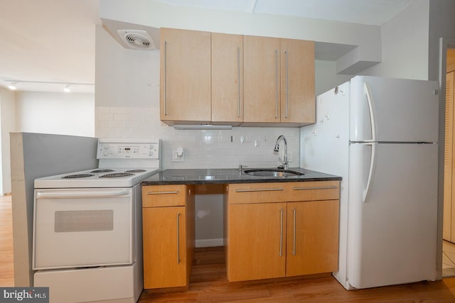 kitchen with light wood-type flooring, backsplash, dark stone counters, white appliances, and sink