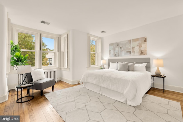 bedroom featuring radiator heating unit and wood-type flooring