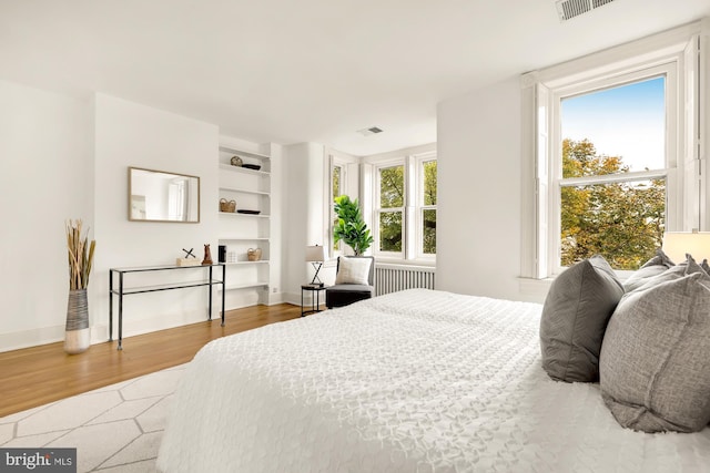 bedroom featuring light hardwood / wood-style floors, multiple windows, and radiator