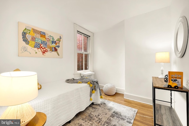 bedroom with light hardwood / wood-style floors and radiator