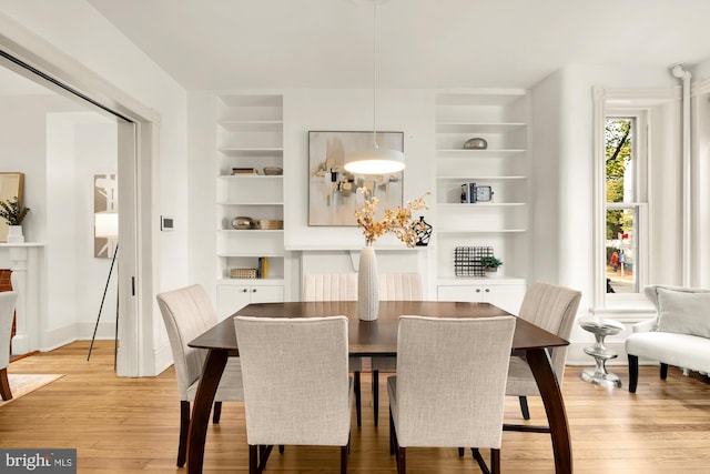 dining room with built in features and light wood-type flooring