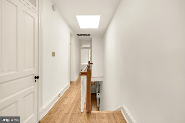 hall featuring a skylight and light wood-type flooring