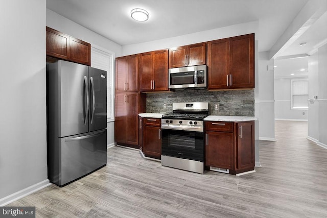 kitchen featuring decorative backsplash, appliances with stainless steel finishes, and light hardwood / wood-style flooring