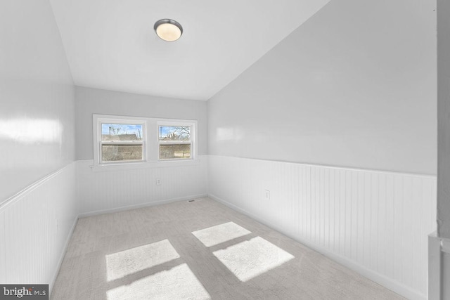 carpeted spare room featuring lofted ceiling