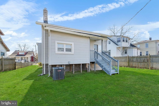 rear view of property with central AC and a lawn