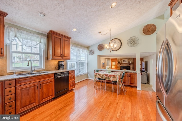 kitchen with sink, vaulted ceiling, a textured ceiling, stainless steel fridge, and dishwasher