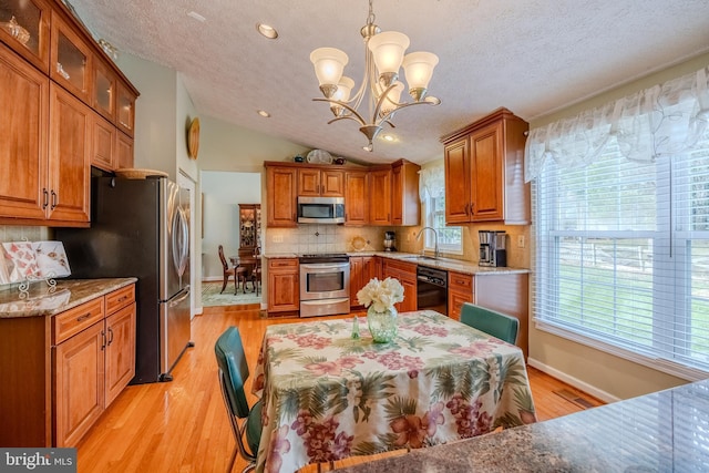 kitchen featuring lofted ceiling, sink, hanging light fixtures, plenty of natural light, and stainless steel appliances