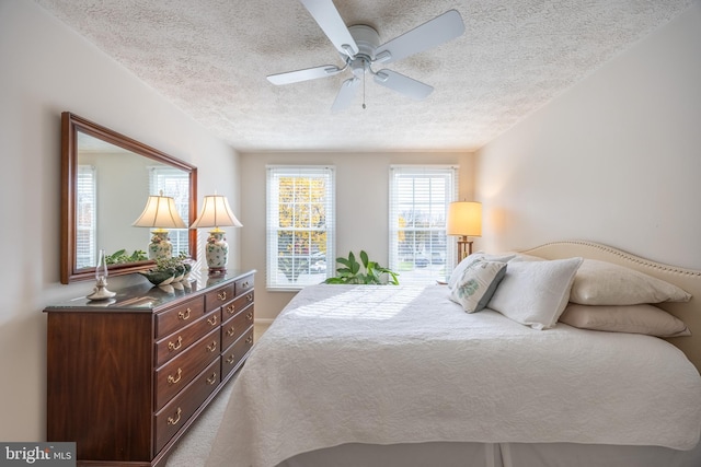 carpeted bedroom featuring ceiling fan and a textured ceiling