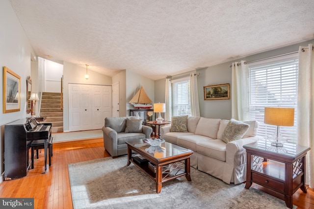 living room featuring lofted ceiling, hardwood / wood-style floors, and a textured ceiling