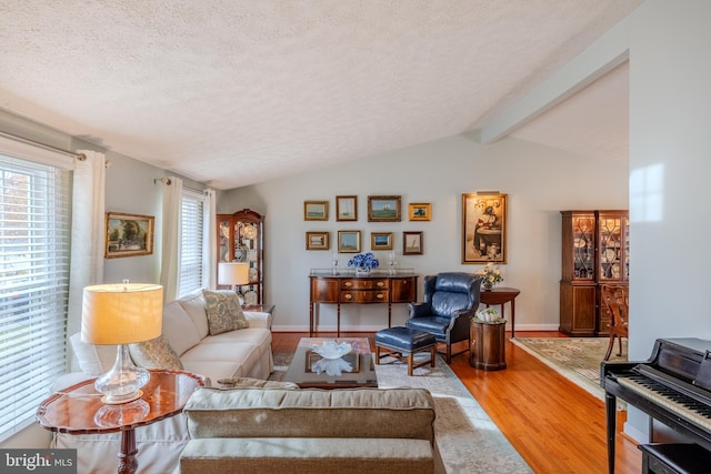 living room with lofted ceiling with beams, hardwood / wood-style floors, and a textured ceiling