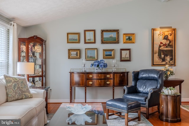 sitting room with hardwood / wood-style flooring, lofted ceiling, and a textured ceiling