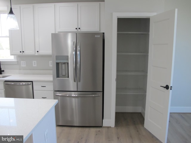 1240 Shore Dr, Colonial Beach, VA 22443 - kitchen featuring appliances with stainless steel finishes, light wood finished floors, white cabinets, light countertops, and hanging light fixtures