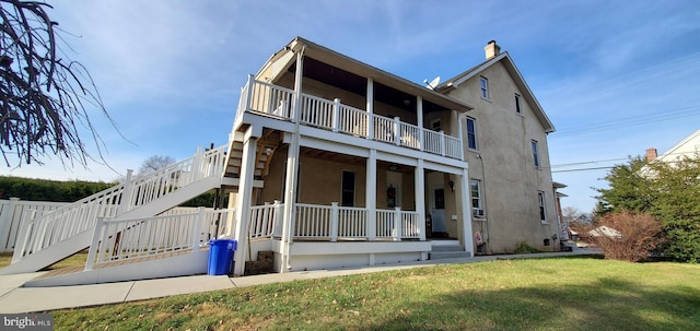 back of house featuring a lawn and a balcony