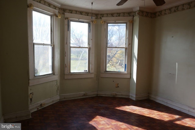 empty room featuring ceiling fan, dark parquet flooring, and crown molding