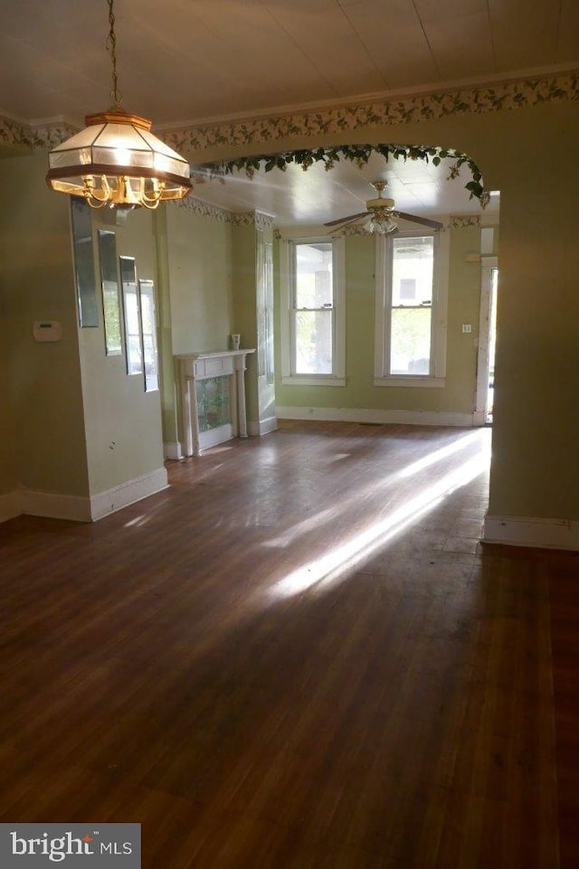 unfurnished room with ceiling fan with notable chandelier and dark hardwood / wood-style flooring