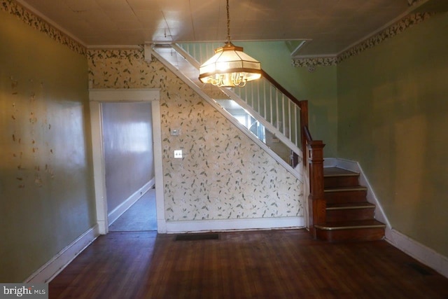 stairway featuring wood-type flooring, an inviting chandelier, and ornamental molding