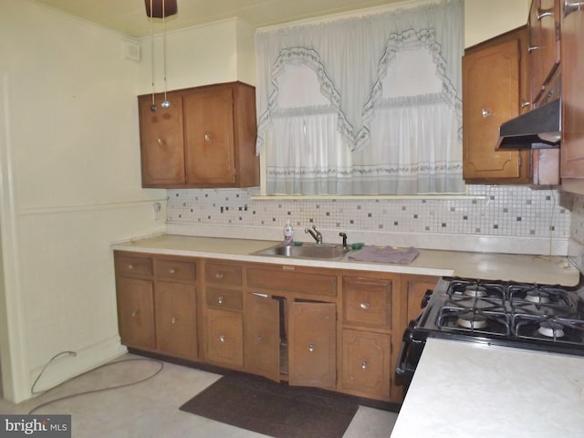 kitchen with backsplash, black range with gas stovetop, sink, and hanging light fixtures