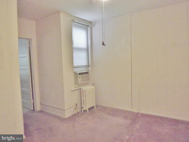 empty room with carpet flooring, cooling unit, and radiator