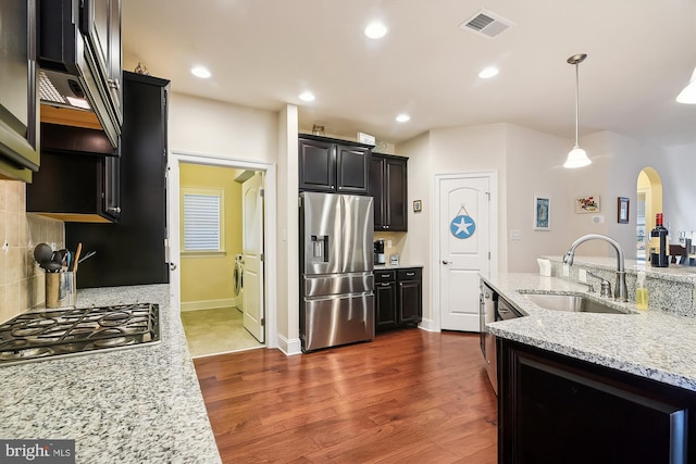 kitchen featuring sink, hanging light fixtures, stainless steel appliances, dark hardwood / wood-style floors, and decorative backsplash