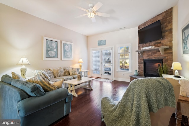 living room featuring a stone fireplace, ceiling fan, and dark hardwood / wood-style flooring