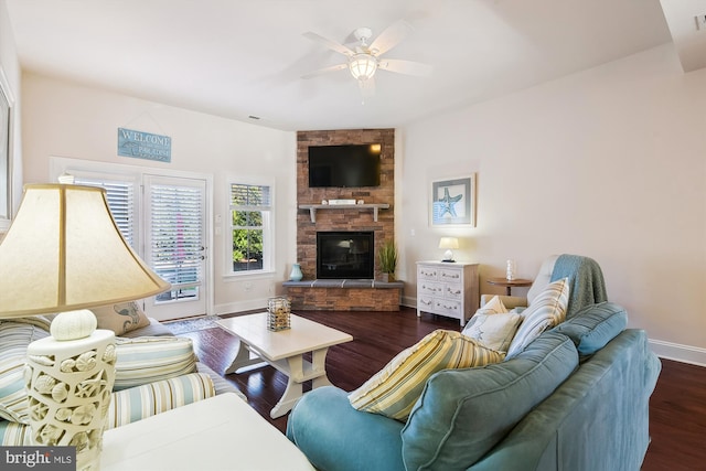 living room featuring dark hardwood / wood-style floors, ceiling fan, and a stone fireplace