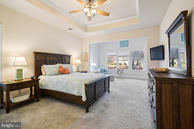 carpeted bedroom with ceiling fan, a raised ceiling, and crown molding