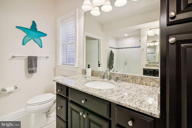 bathroom with vanity, a shower with shower door, and toilet