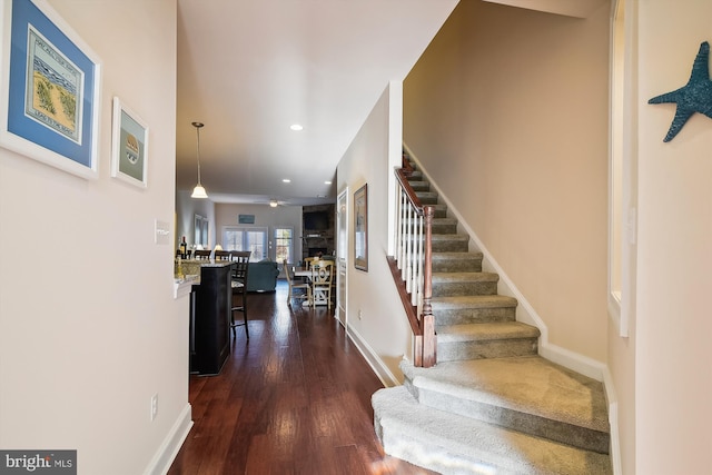 stairs with hardwood / wood-style floors and ceiling fan