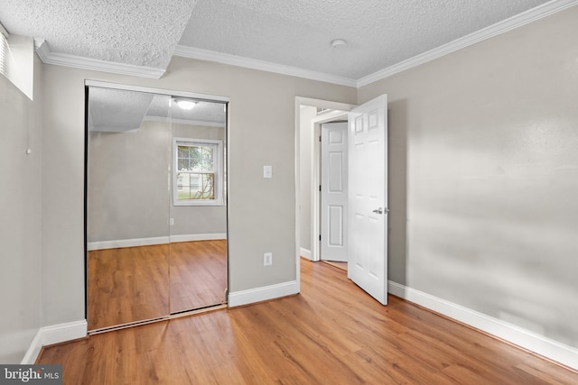 unfurnished bedroom with a textured ceiling, light hardwood / wood-style flooring, and ornamental molding