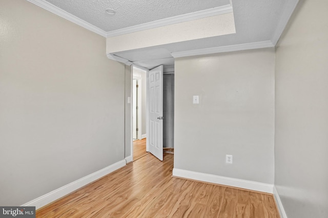 empty room featuring a textured ceiling, light hardwood / wood-style floors, and crown molding