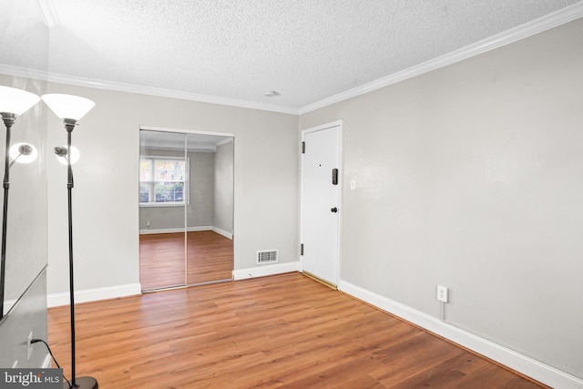 unfurnished room with ornamental molding, a textured ceiling, and hardwood / wood-style flooring