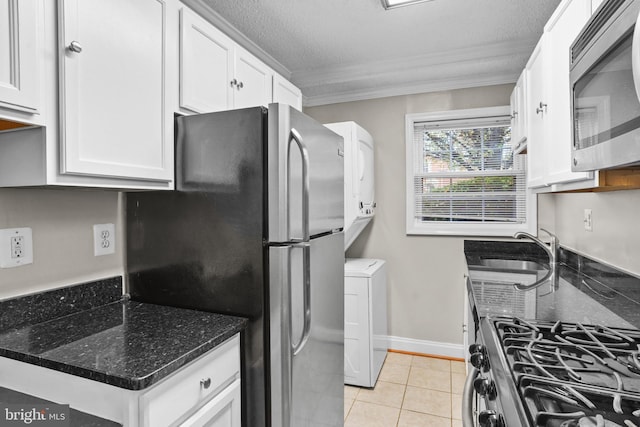 kitchen with sink, dark stone countertops, light tile patterned floors, white cabinetry, and stainless steel appliances