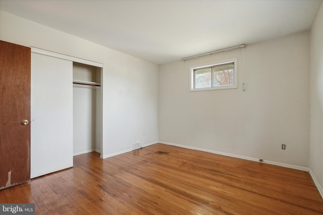 unfurnished bedroom featuring a closet and hardwood / wood-style flooring