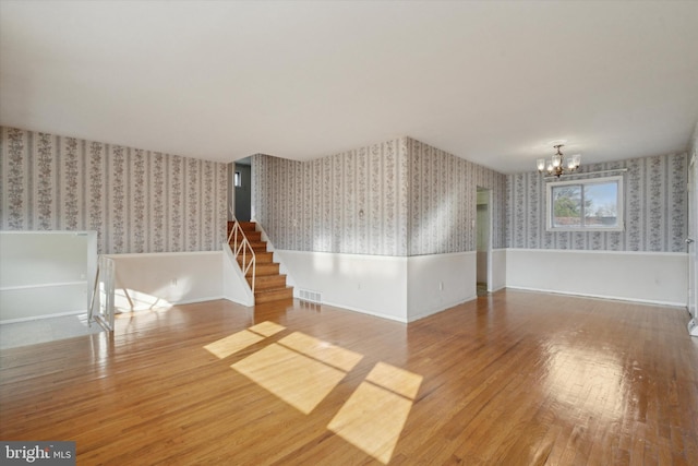 spare room featuring a chandelier and hardwood / wood-style flooring