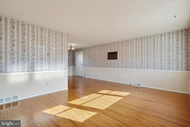 spare room featuring hardwood / wood-style flooring and an inviting chandelier