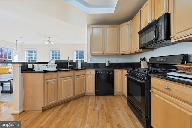 kitchen featuring sink, kitchen peninsula, black appliances, ceiling fan with notable chandelier, and light wood-type flooring