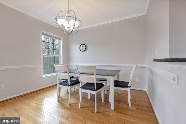 dining room with a notable chandelier, light wood-type flooring, and crown molding