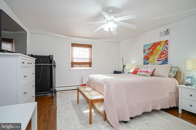 bedroom with hardwood / wood-style floors, a baseboard radiator, and ceiling fan