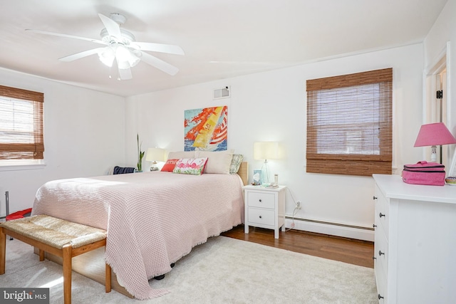 bedroom featuring ceiling fan, light hardwood / wood-style flooring, and a baseboard radiator