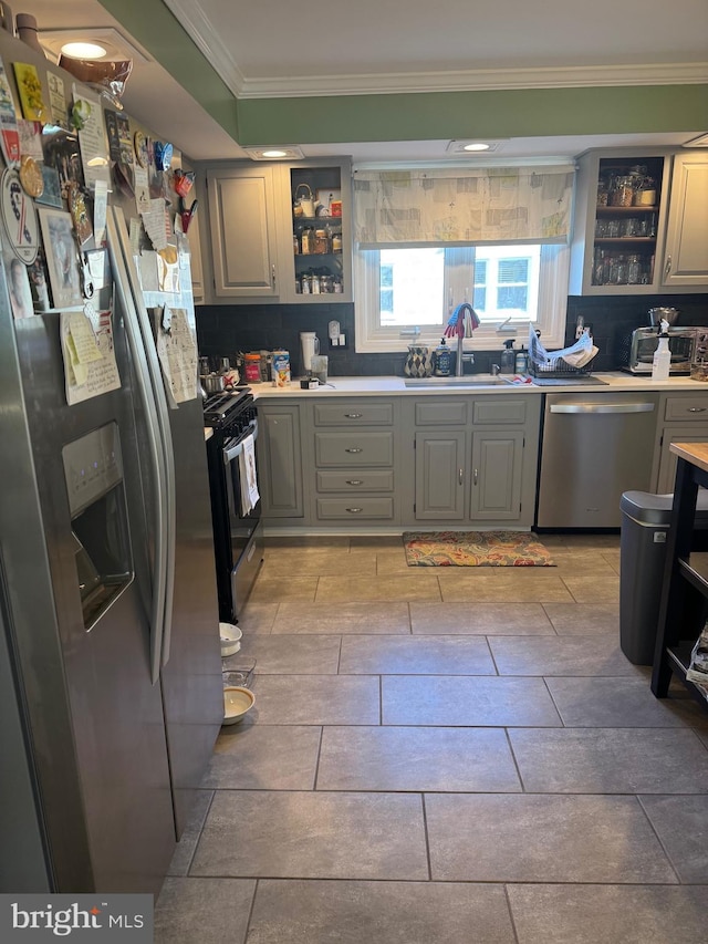 kitchen featuring stainless steel appliances, crown molding, gray cabinetry, and sink