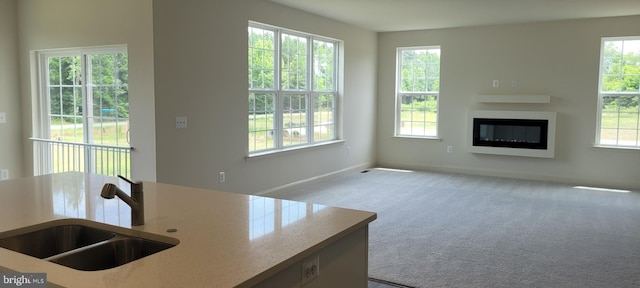 unfurnished living room with light carpet, plenty of natural light, and sink