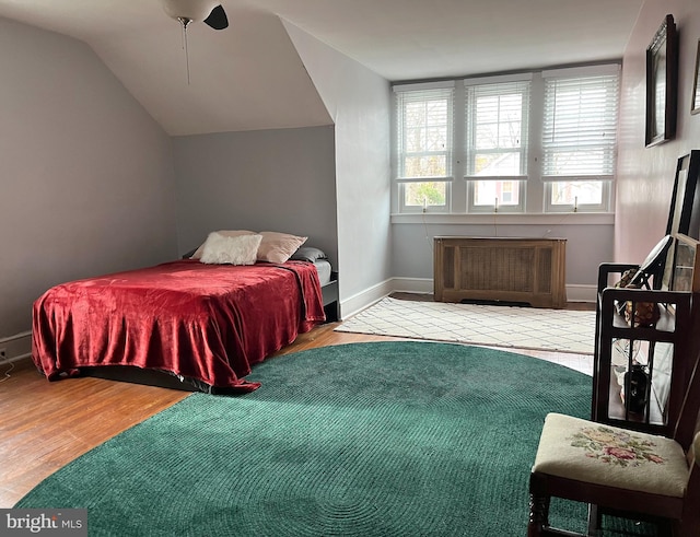 bedroom featuring multiple windows, ceiling fan, light hardwood / wood-style floors, and lofted ceiling