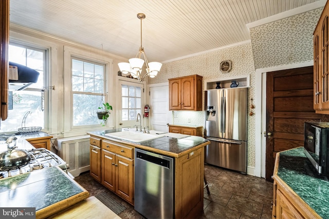 kitchen featuring appliances with stainless steel finishes, sink, a notable chandelier, hanging light fixtures, and an island with sink