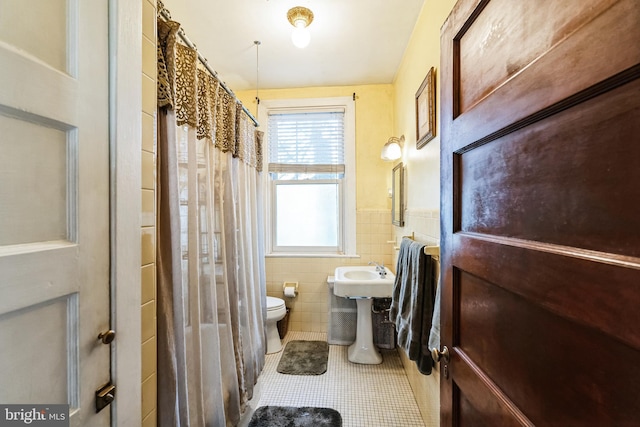 bathroom featuring tile patterned flooring, sink, toilet, and tile walls