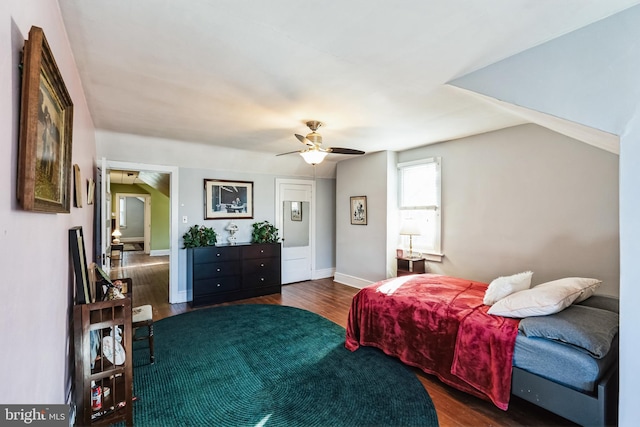 bedroom with ceiling fan, dark wood-type flooring, and vaulted ceiling