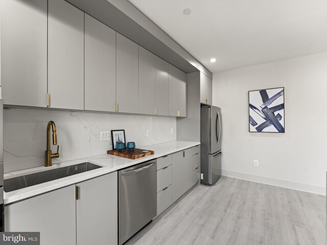 kitchen with appliances with stainless steel finishes, gray cabinets, and light hardwood / wood-style floors