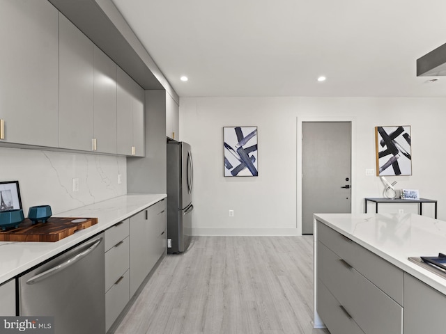 kitchen featuring gray cabinetry, backsplash, stainless steel appliances, and light hardwood / wood-style flooring