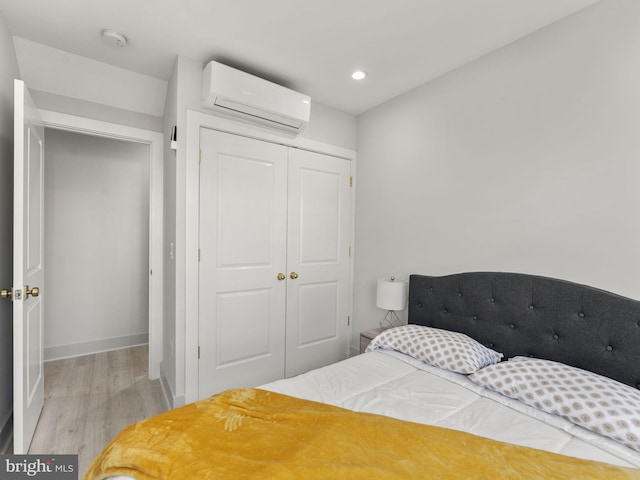 bedroom featuring a wall mounted AC, light wood-type flooring, and a closet