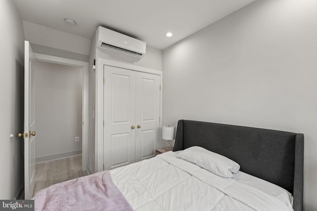 bedroom with light wood-type flooring, a wall unit AC, and a closet