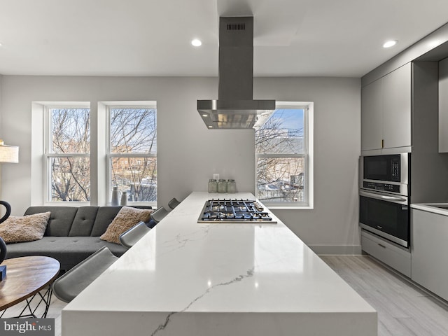 kitchen with gray cabinetry, a wealth of natural light, extractor fan, and appliances with stainless steel finishes